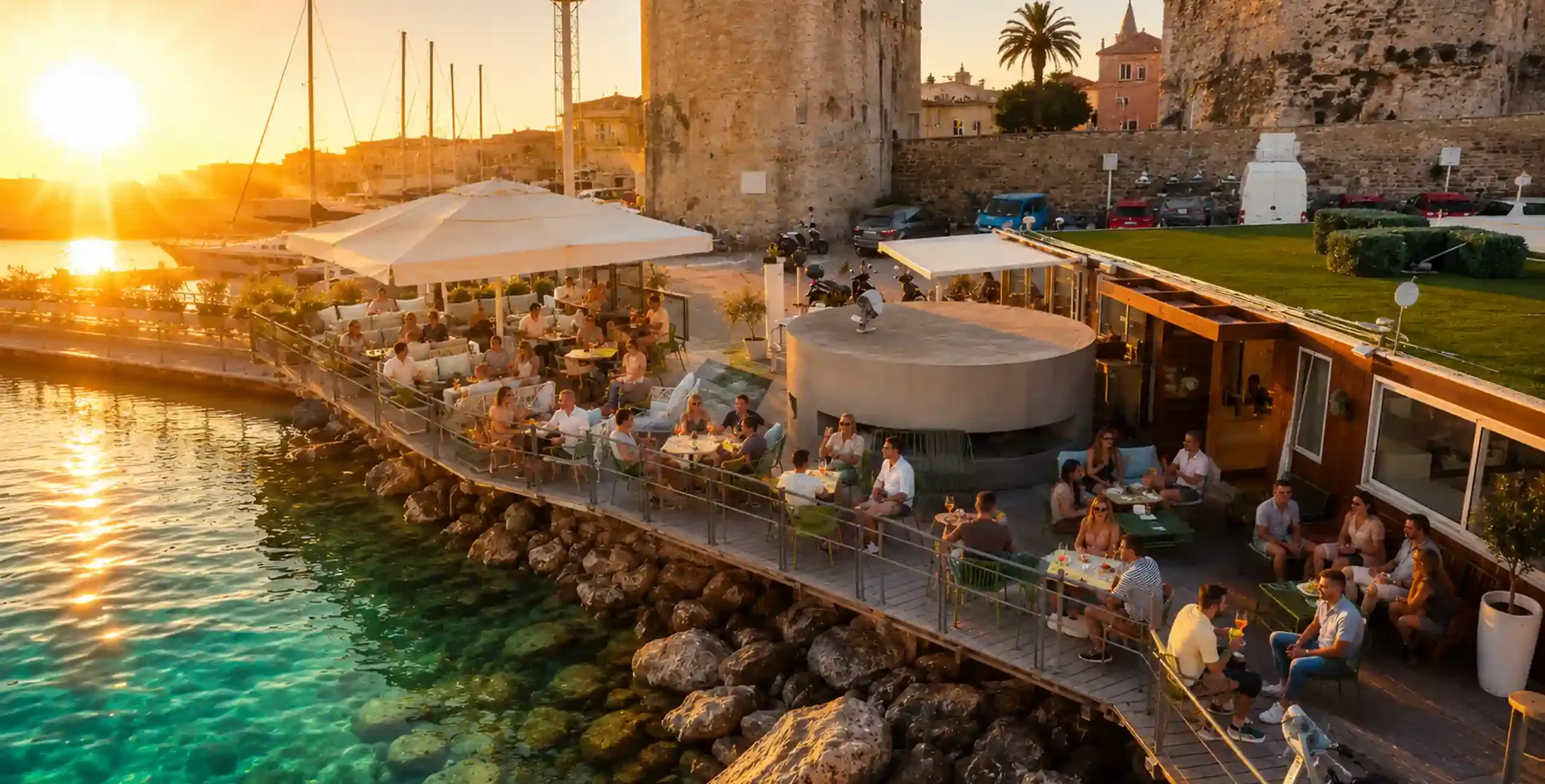 Aquatica Lounge Bar nel Porto di Alghero con vista sulla Marina e sulle imbarcazioni al tramonto.