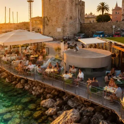 Aquatica Lounge Bar nel Porto di Alghero con vista sulla Marina e sulle imbarcazioni al tramonto.